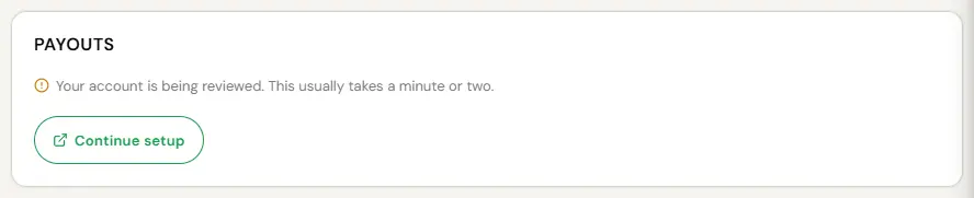 The same Payouts card after the Stripe form was finished and nothing more is due. An amber note reads: Your account is being reviewed. This usually takes a minute or two. A Continue setup button returns to Stripe. No bank details are shown.